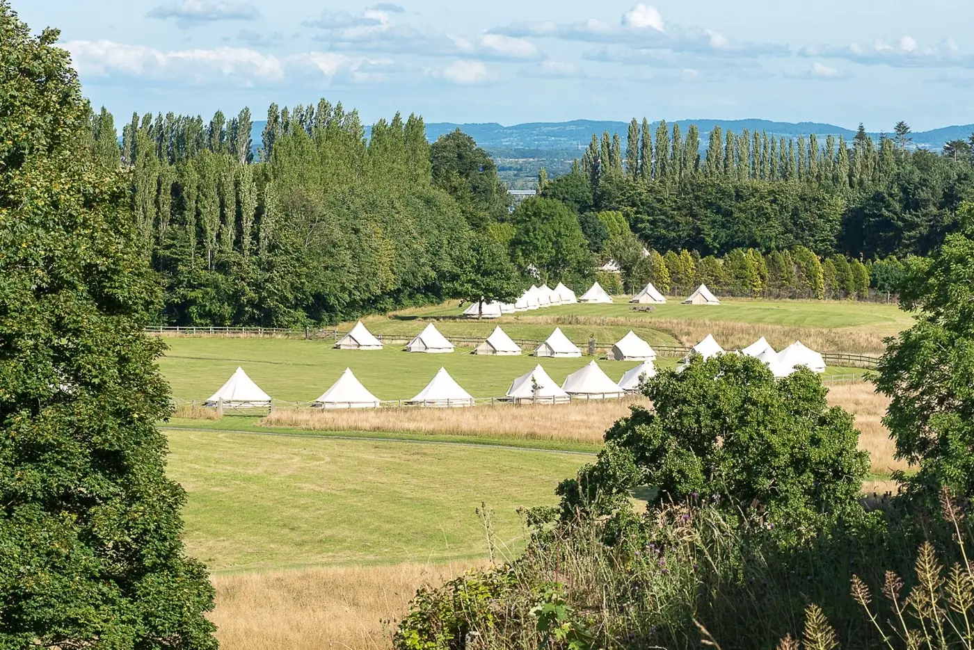 White bell tents put up by The Glamping Group