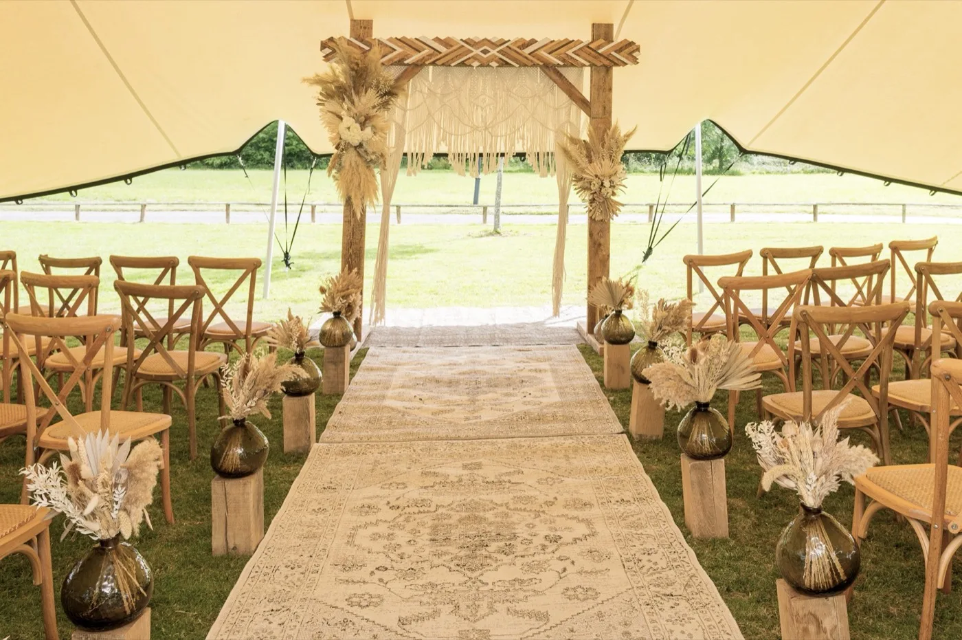 An outdoor wedding ceremony under a stretch tent put up by The Glamping Group