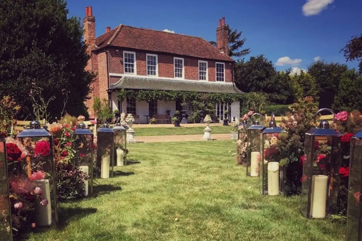 Country manor set in the Hertfordshire countryside surrounded by trees and blue sky.