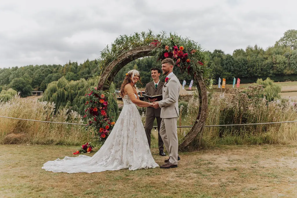 bride and groom in front of circular floral arch